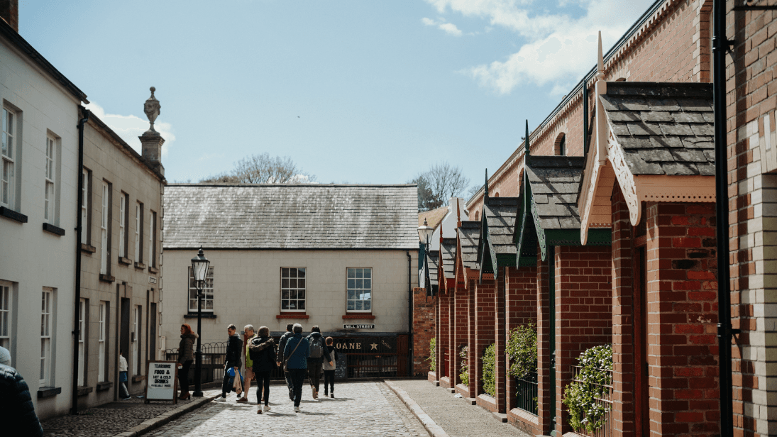A group of visitors walking down a cobbled street at Ulster Folk Museum
