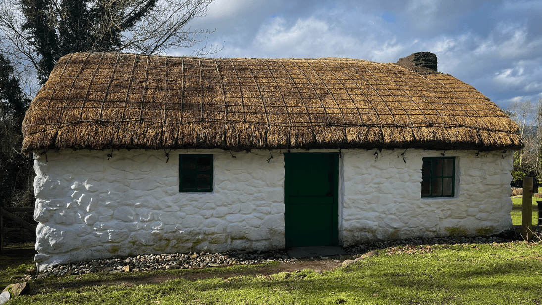 A thatched cottage stands in the sun.
