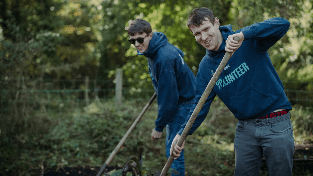 Two men digging and smiling at the camera at ulster folk museum 