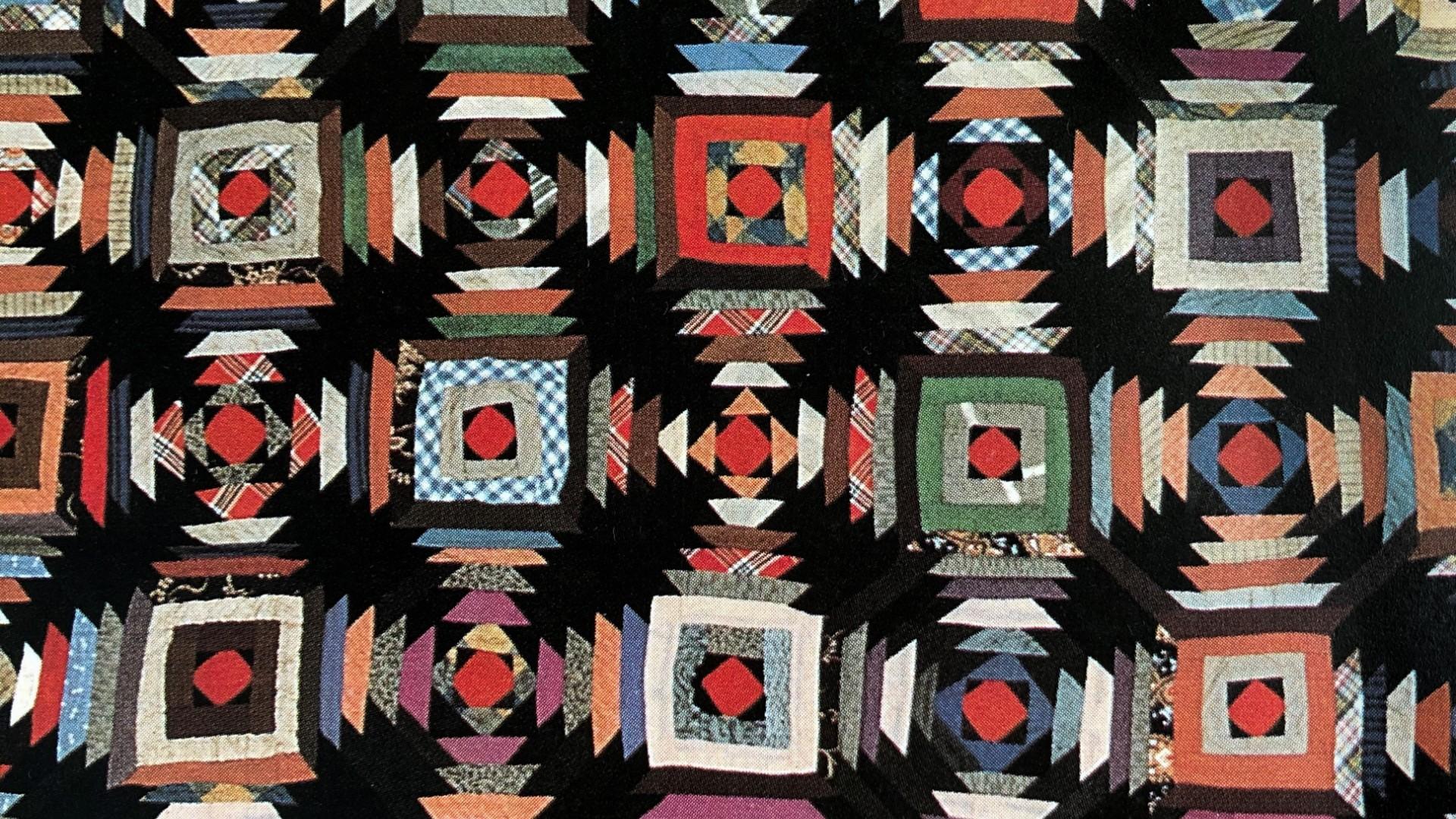 A black quilt with colourful pattern work.