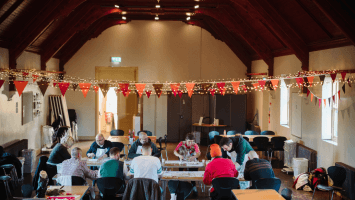 Parochial Hall decorated with lights and bunting and group of people taking part in crafts