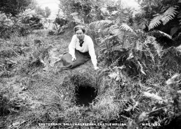A woman sits above the opening to a souterrain.