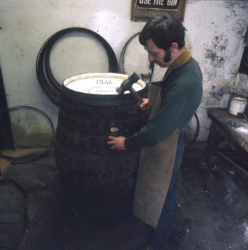 A man stands beside a barrel he is in the process of making.