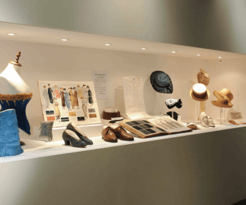 A shot of an exhibition with a corset, some shoes, and hats.