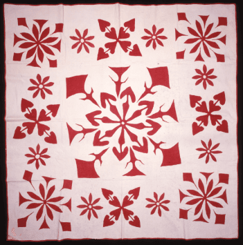 A white and red quilt with patterns like snowflakes on it.