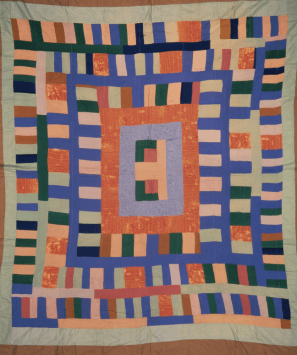 A colourful quilt lined with orange, in stripey patterns.