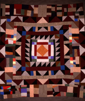 A wildly patterned quilt surrounding an orange diamond centre.