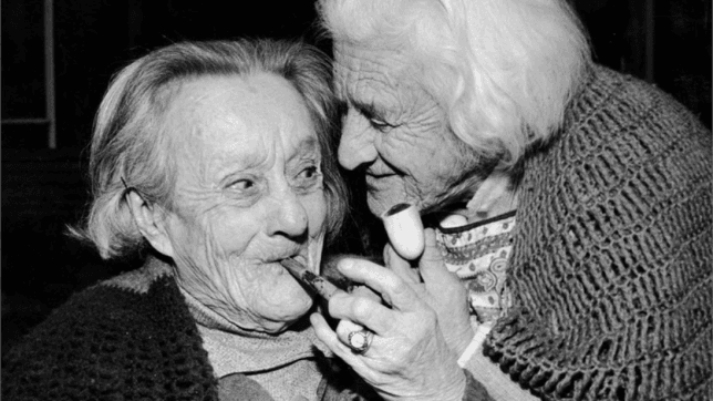 Two elderly women smoking pipes
