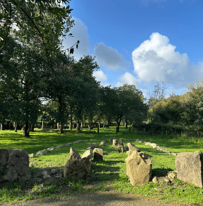 A long view of a Neolithic court tomb, with stones standing tall in front.
