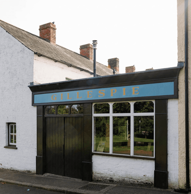 A carpenter's shop with a blue sign, with gold letters reading 'Gillespie'.