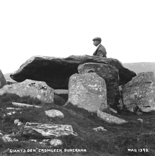 A man stands behind a dolmen, an archaeological monument.