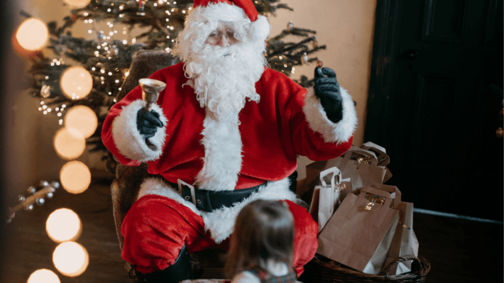 a man dressed as santa claus with a little girl looking up at him