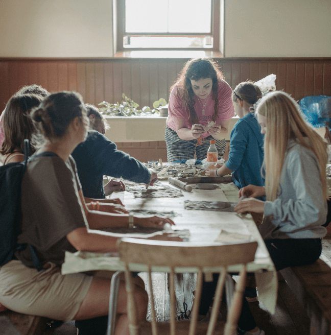A group of girls sit around a table crafting.