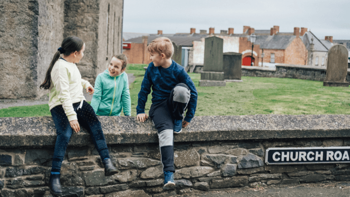 three children sitting on the wall of ulster folk museum 