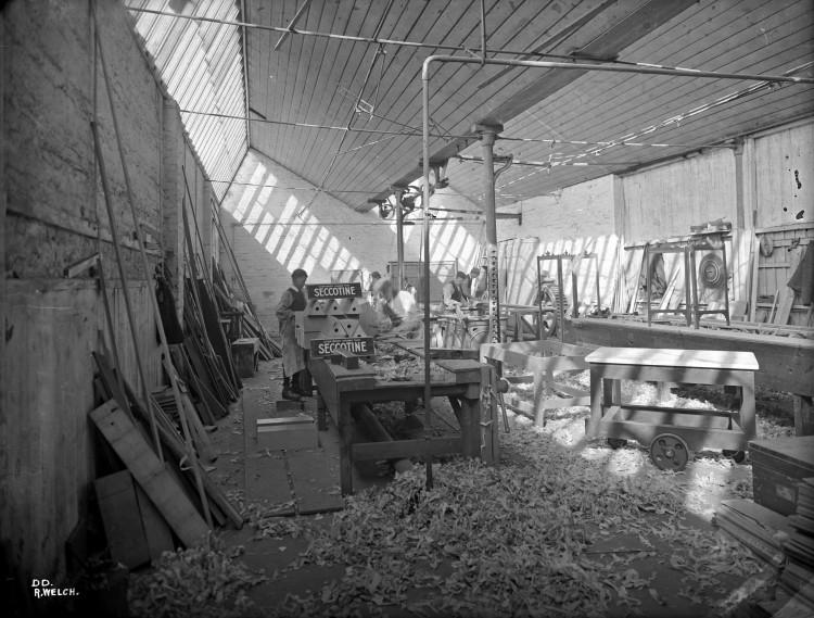 A view of a woodworking workshop, with a lot of sawdust on the ground.