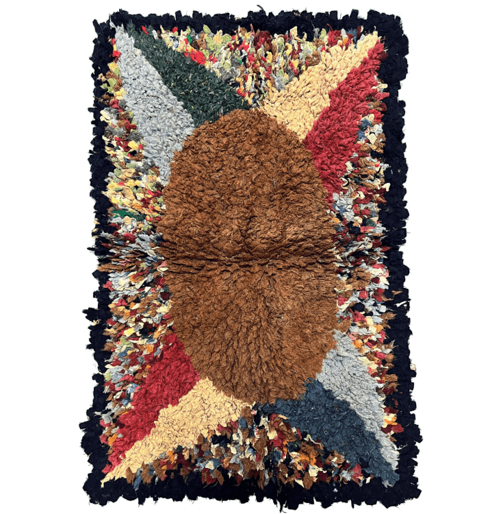 A colourful rug with a golden oval centre. Two red and yellow and two blue and green triangles eminate from the oval. It has a black edge.
