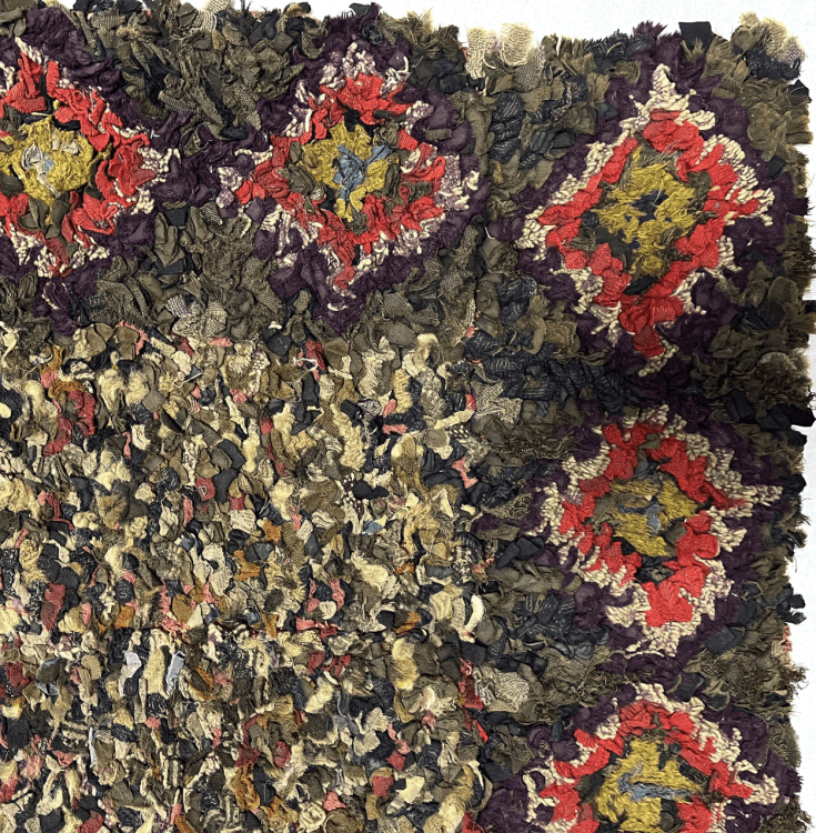 A detailed corner of a rug. The inner rectangle is multicoloured. The outer rectangle has multicoloured diamond shapes decorating the rug every few inches.