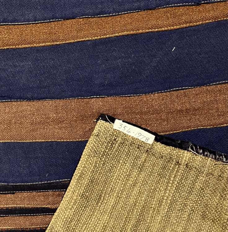 A striped rag rug showing the backing material, which is burlap.