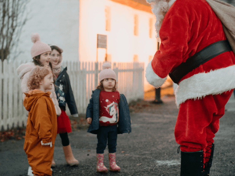 four small children smiling at a man dressed as santa claus at ulster folk museum