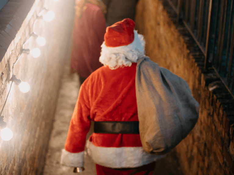 A man dressed as santa claus with his back to the camera walking down steps